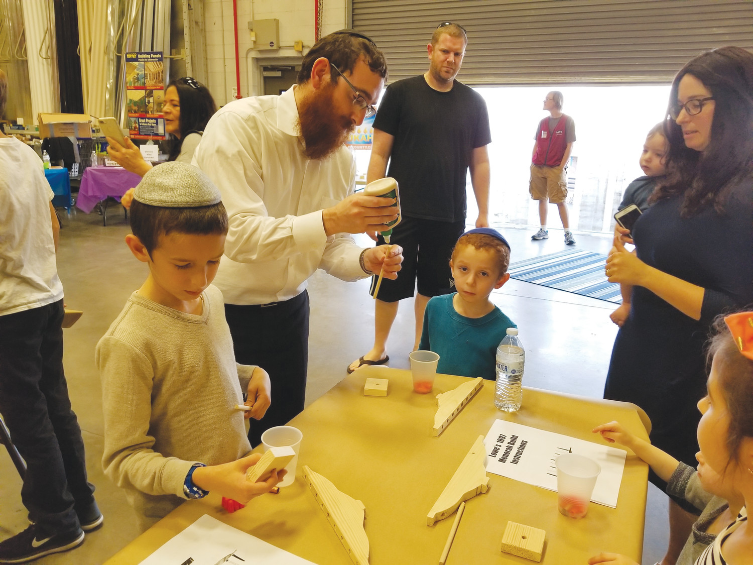 Rabbi Shmuly Feldman, second from left, assists children with making menorahs in preparation for the annual celebration of Hanukkah at a workshop held Dec. 2 at Lowe’s on Kingsley Avenue.