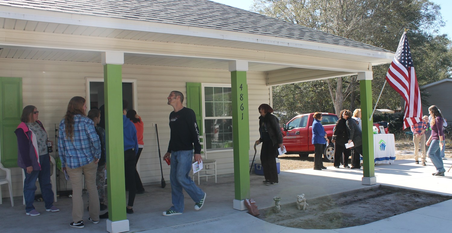 Family, friends and supporters and staff of Clay County Habitat for Humanity tour Stephanie Mabey’s new home Jan. 19 during a dedication ceremony. Mabey logged almost 300 hours in helping build the home.